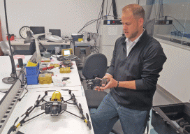 Applications engineer Jeff DeBoer demonstrates interchangeable payload options enabled by the “V” airframe of the new UAS, Falcon 8. Two models are offered: GeoEXPERT for surveying and InspectionPRO for industrial inspection.