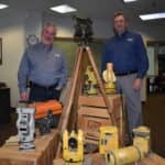 Mark Contino, vice president of North American retail distribution at Topcon Positioning Systems (left) and Ken Shersty, director of hardware sales for TSS, in a small museum of survey gear in The Solutions Store Kent, Washington, location.