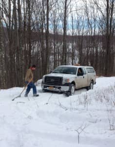 RETTEW surveyor John Vogt shovels snow in Delaware County so he can measure the boundary of land acquired to protect the watershed. 