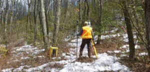 Kirk Norton, NPS land surveyor for the AT, sets up a foresight in Pennsylvania with help from members of the Potomac Appalachian Trail club on the hill above him. Credit: Nicole Wooten.