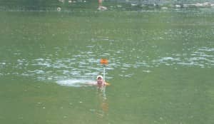 Nathan Harris, of Allegheny Surveys, swims in place while locating river bottom cross sections downstream of the dam.