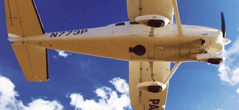 Looking up into the belly of a Cessna 206 airplane. The aerial photography camera is looking down through the hole.